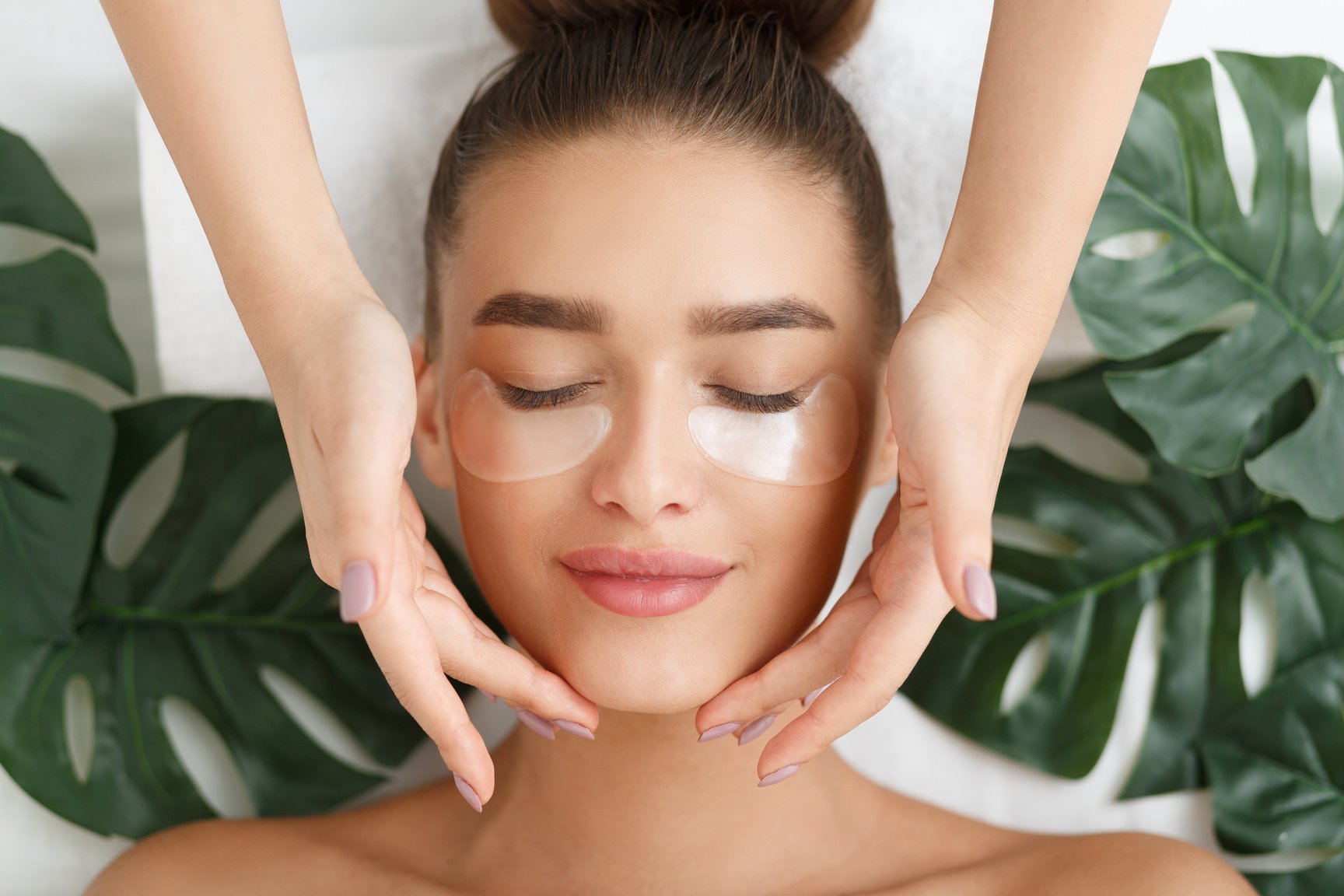 Woman with eye patches having face massage